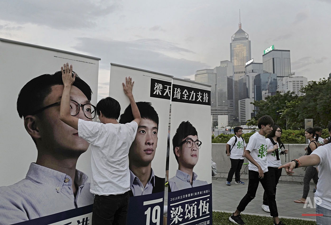  In this Aug. 28, 2016 photo, a supporter holds on to election banners for radical localist group Youngspiration's candidate Baggio Leung, center, during a pre-election rally in Hong Kong. (AP Photo/Vincent Yu) 