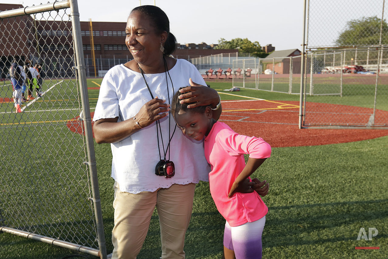  In this July 12, 2016 photo, Brooke Sheppard, 8, is hugged by one of her coaches Karel Lancaster, during training at Boys and Girls High School in the Brooklyn borough of New York. Every morning, Brooke and her two young sisters wake up together wit