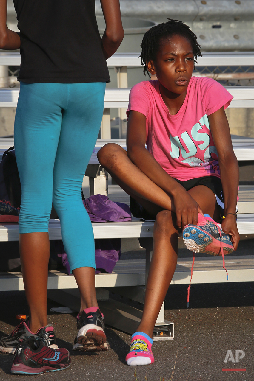  In this Wednesday, July 20, 2016 photo, Rainn Sheppard, 10, puts on her spikes as she prepares for track practice at Boys and Girls High School in the Brooklyn borough of New York. Rainn and her two sisters Tai Sheppard, 11, and Brooke Sheppard, 8, 