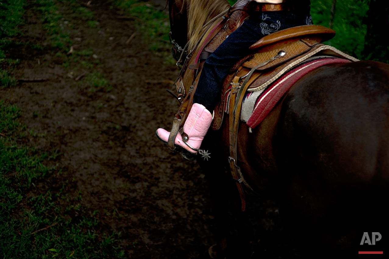  In this July 29, 2016 photo, cowgirl Dariadna Corujo rides her horse near a farm in Sancti Spiritus, central Cuba. At the tender age of 6, Dariadna is already an expert barrel racer and calf roper, wearing pink boots as she competes in rodeos on the