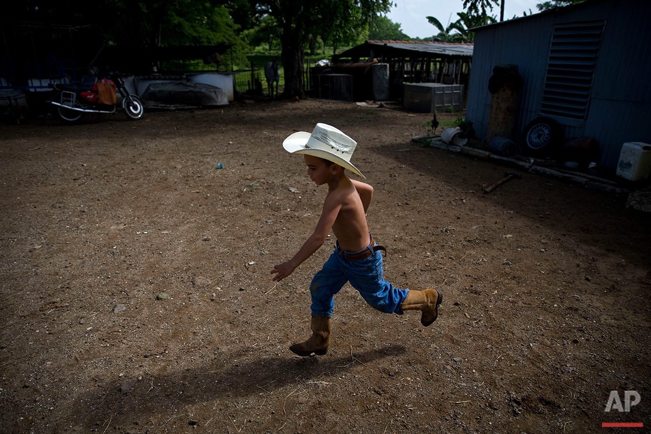  In this July 29, 2016 photo, 5-year-old cowboy David Obregon runs across the yard of his parents farm in Sancti Spiritus, central Cuba. In the Cuban countryside, many children learn to ride a horse before they learn to ride a bicycle. Those who grow