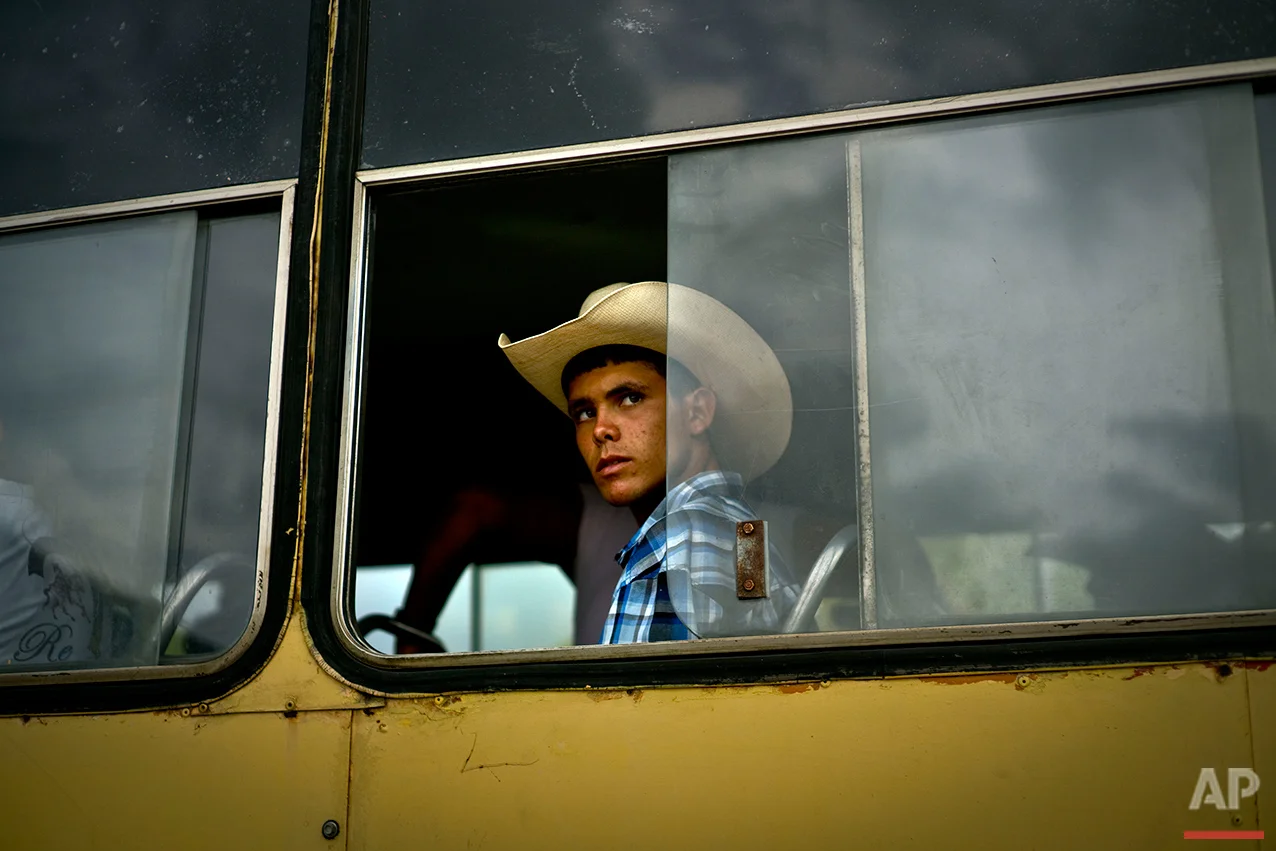  In this July 29, 2016 photo, a young cowboy looks out from a bus window as he waits to be transported via bus to an improvised rodeo event at a farm in Sancti Spiritus, central Cuba. In Sancti Spiritus’ cattle country, 80 children are enrolled in th