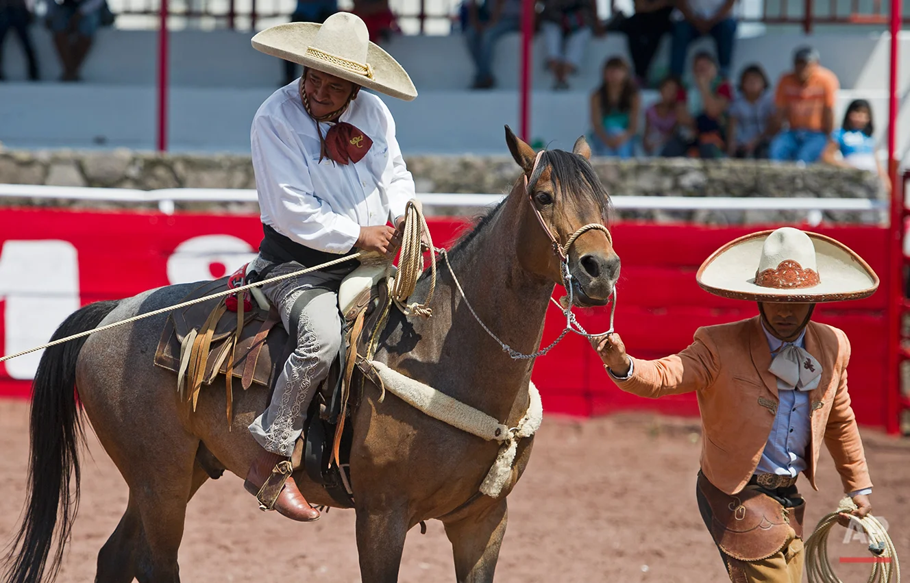 In this July 10, 2016 photo, with the help of a guide and his brace gripping his lower back, charro or Mexican cowboy Salvador Espinosa grips his lasso before downing a young bull at the Mexican rodeo arena in Cuautitlán Izcalli, Mexico. Espinoza ne