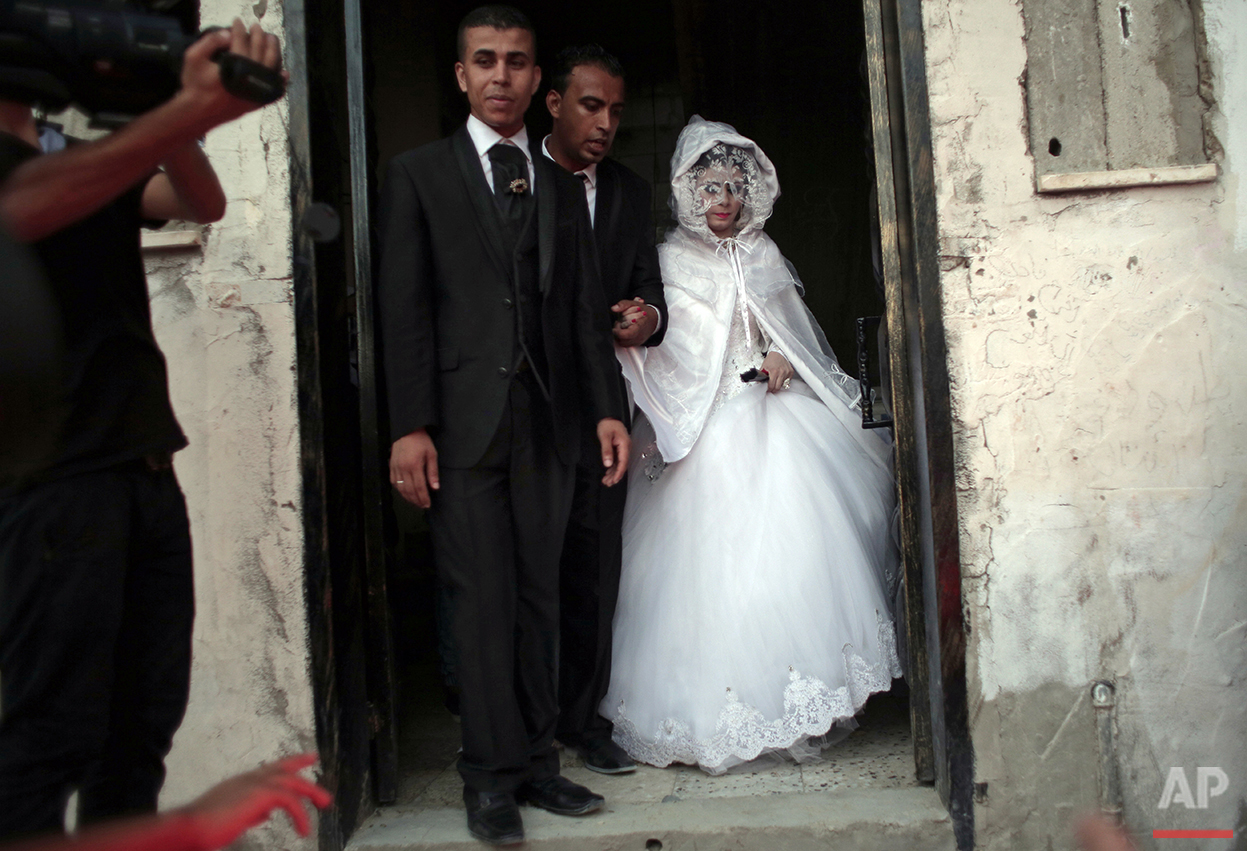  In this Saturday, July 31, 2016 photo, Palestinian groom Saed Abu Aser, 22, walks with his bride Falasteen, out of her family house to the wedding hall celebrating their wedding in Gaza City. Weddings in Gaza have emerged as a welcome celebration th