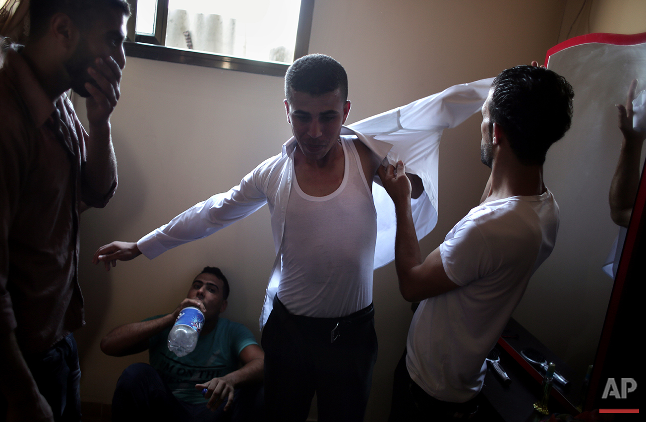  In this Saturday, July 31, 2016 photo, friends of Palestinian groom Saed Abu Aser help him wear a tuxedo in the family house as a tradition preparing him for his wedding in Gaza City. (AP Photo/ Khalil Hamra) 