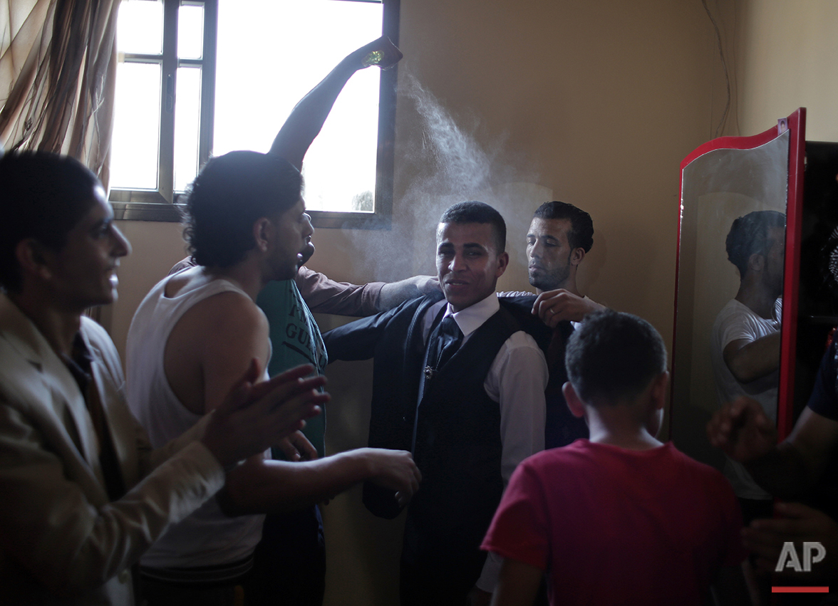  In this Saturday, July 31, 2016 photo, friends of Palestinian groom Saed Abu Aser help him wear a tuxedo in the family house as a tradition preparing him for his wedding in Gaza City. (AP Photo/Khalil Hamra) 