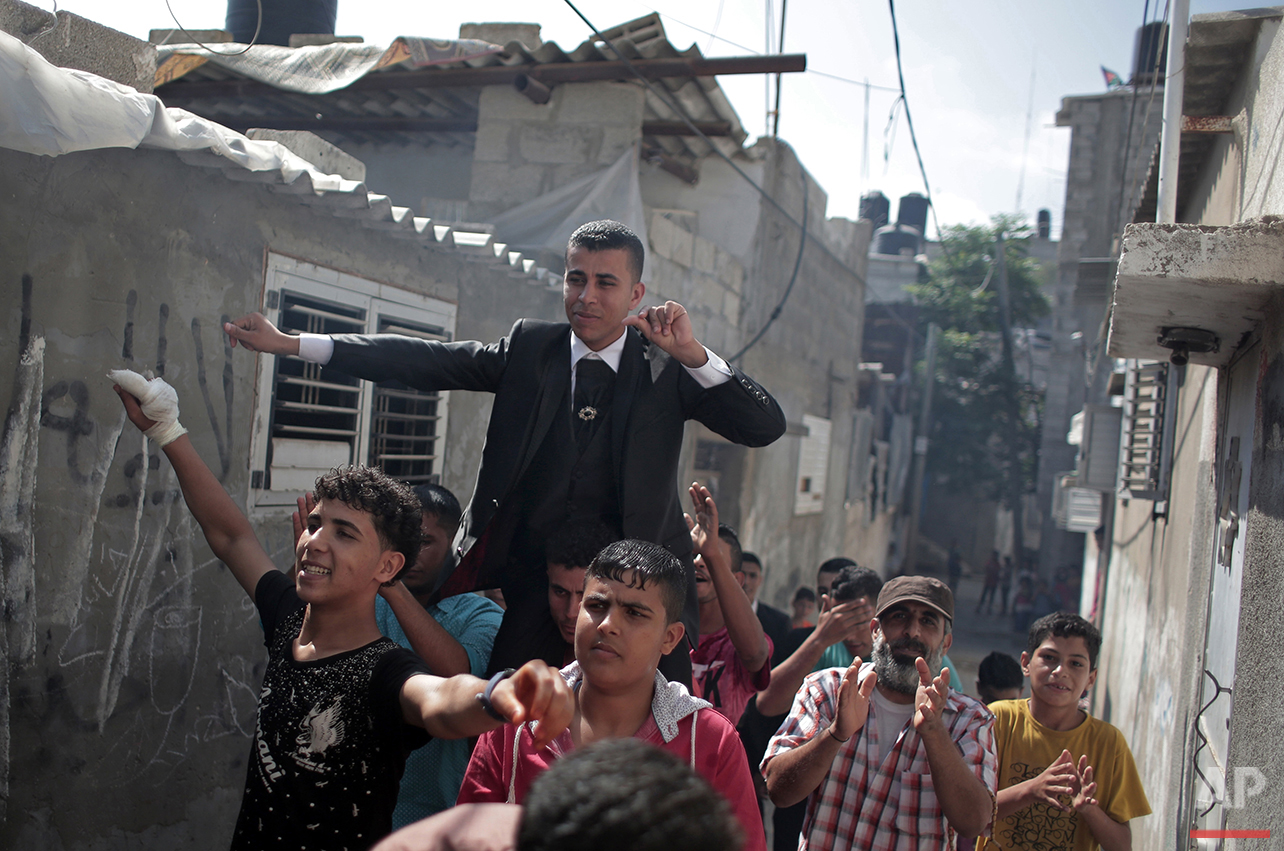  In this Saturday, July 31, 2016 photo, friends and relatives of Palestinian groom Saed Abu Aser carry him on shoulders while dancing around the neighborhood before his wedding party in Gaza City. (AP Photo/Khalil Hamra) 