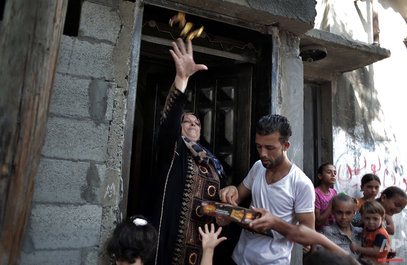  In this Saturday, July 31, 2016 photo, a woman throws candy as friends of Palestinian groom Saed Abu Aser carry him on their shoulders while dancing around the neighborhood before his wedding party in Gaza City. (AP Photo/Khalil Hamra) 