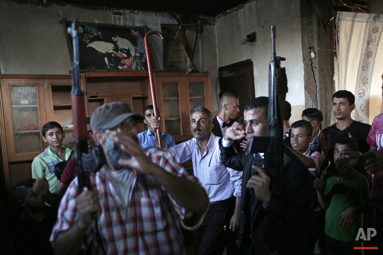  In this Saturday, July 31, 2016 photo, Palestinian groom Saed Abu Aser, right,  dance with relatives holding guns in the family house during his wedding party in Gaza City. (AP Photo/ Khalil Hamra) 