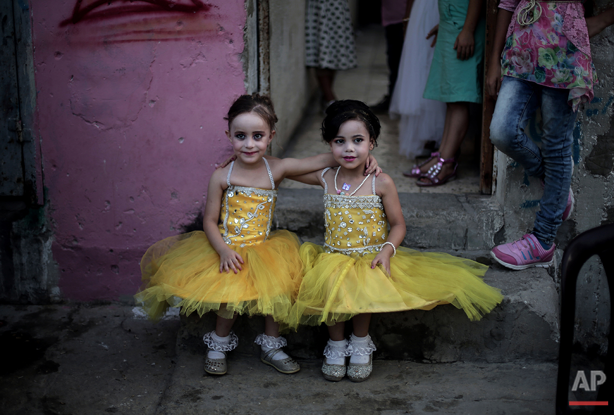  In this Saturday, July 31, 2016 photo, two dressed up girls pose for a picture as they sit in front of the family house during the wedding party of Palestinian groom Saed Abu Aser in Gaza City. (AP Photo/ Khalil Hamra) 