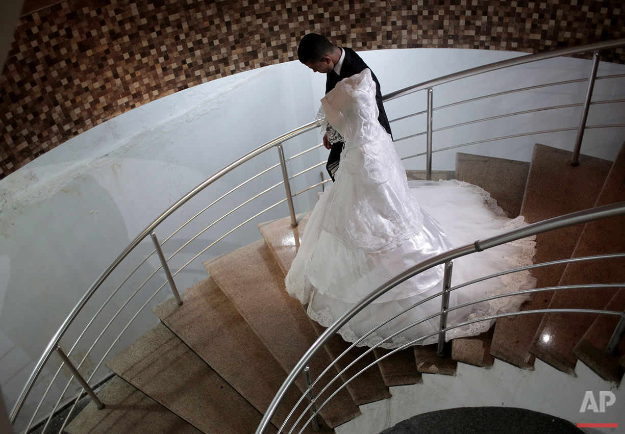  In this Saturday, July 31, 2016 photo, Palestinian groom Saed Abu Aser and his bride, Falasteen, take the stairs down to the wedding hall in Gaza City. (AP Photo/Khalil Hamra) 