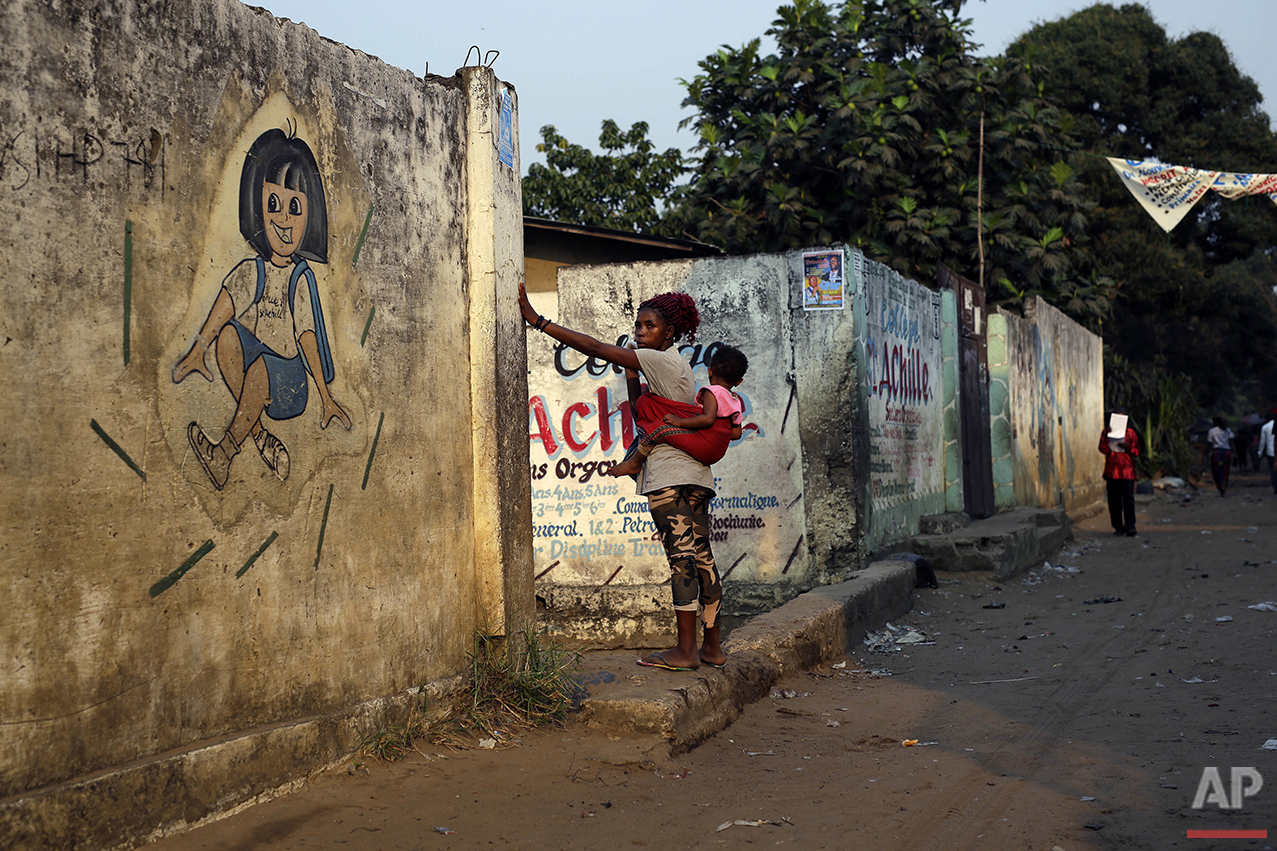  In this photo taken Wednesday July 20, 2016, residents of the Kisenso district of Kinshasa, Democratic Republic of Congo, walk by a kindergarten. (AP Photo/Jerome Delay) 