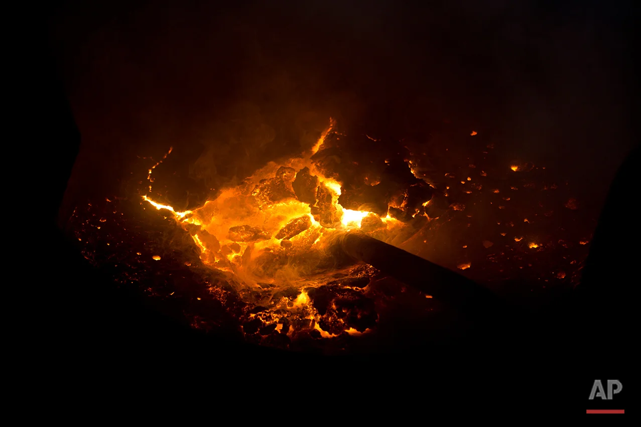 In this Aug. 3, 2016 photo, collected aluminum waste is liquified in a furnace to be cast into blocks on the outskirts of Dhaka, Bangladesh. A large swath of land not far from the Buriganga River is dotted with makeshift tents that are home to men and women who travel far from home to work 12 hours a day recycling cans, industrial ash and medicine blister packets into raw aluminum. The work is difficult and dangerous. The workers have no safety equipment or masks to protect themselves from the fumes and aluminum dust. (AP Photo/ A.M. Ahad)