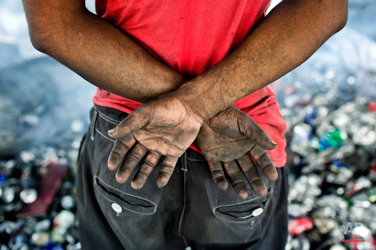 In this Aug. 3, 2016 photo, Ruhul Amin, pauses as he sorts aluminum cans on the outskirts of Dhaka, Bangladesh. A large swath of land not far from the Buriganga River is dotted with makeshift tents that are home to men and women who travel far from home to work 12 hours a day recycling cans, industrial ash and medicine blister packets into raw aluminum. The work is difficult and dangerous. The workers have no safety equipment or masks to protect themselves from the fumes and aluminum dust. (AP Photo/ A.M. Ahad)
