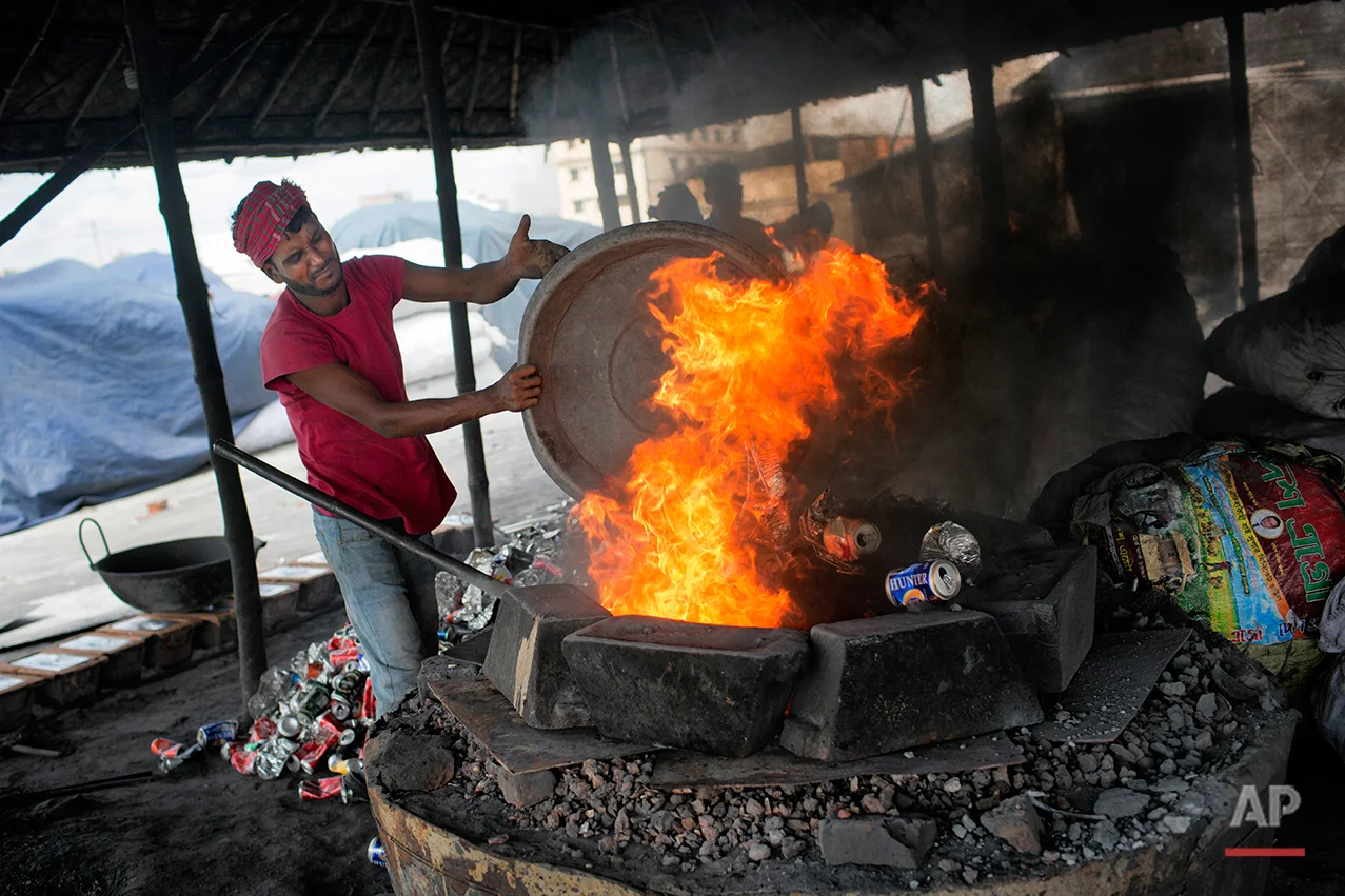In this Aug. 3, 2016 photo, Monir Hossain melts recycled aluminum on the outskirts of Dhaka, Bangladesh. A large swath of land not far from the Buriganga River is dotted with makeshift tents that are home to men and women who travel far from home to work 12 hours a day recycling cans, industrial ash and medicine blister packets into raw aluminum. The work is difficult and dangerous. The workers have no safety equipment or masks to protect themselves from the fumes and aluminum dust. (AP Photo/A.M. Ahad)