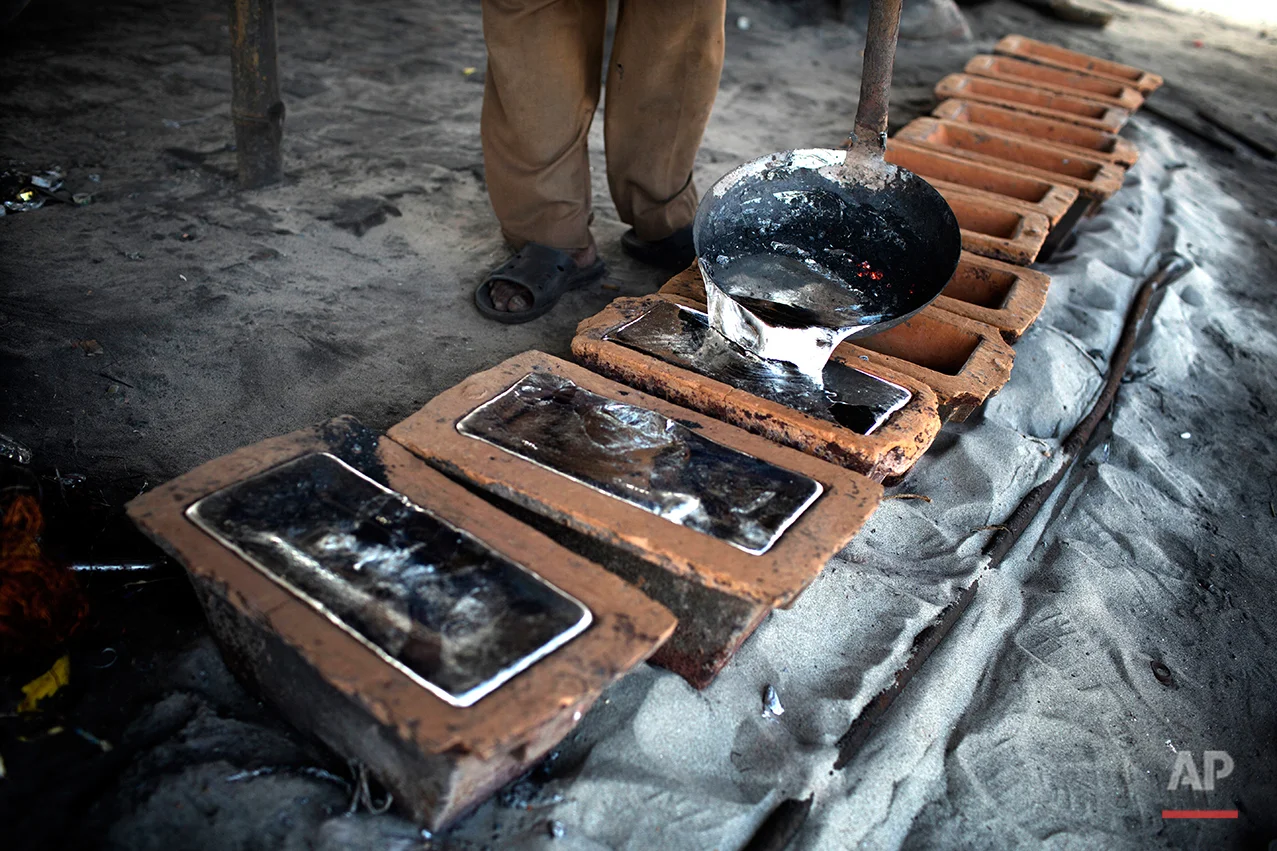 In this Aug. 3, 2016 photo, a worker pours liquid aluminum into casts at a recycling factory on the outskirts of Dhaka, Bangladesh. A large swath of land not far from the Buriganga River is dotted with makeshift tents that are home to men and women who travel far from home to work 12 hours a day recycling cans, industrial ash and medicine blister packets into raw aluminum. The work is difficult and dangerous. The workers have no safety equipment or masks to protect themselves from the fumes and aluminum dust. (AP Photo/A.M. Ahad)