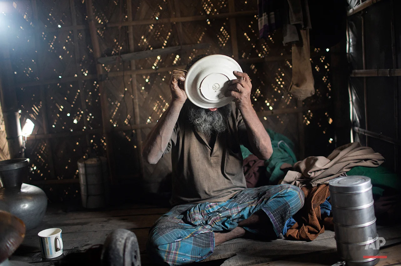 In this Aug. 6, 2016 photo, Mohammad Motaleb finishes a meal at his makeshift home near an aluminum recycling factory on the outskirts of Dhaka, Bangladesh. A large swath of land not far from the Buriganga River is dotted with makeshift tents that are home to men and women who travel far from home to work 12 hours a day recycling cans, industrial ash and medicine blister packets into raw aluminum. The work is difficult and dangerous. The workers have no safety equipment or masks to protect themselves from the fumes and aluminum dust. (AP Photo/ A.M. Ahad)