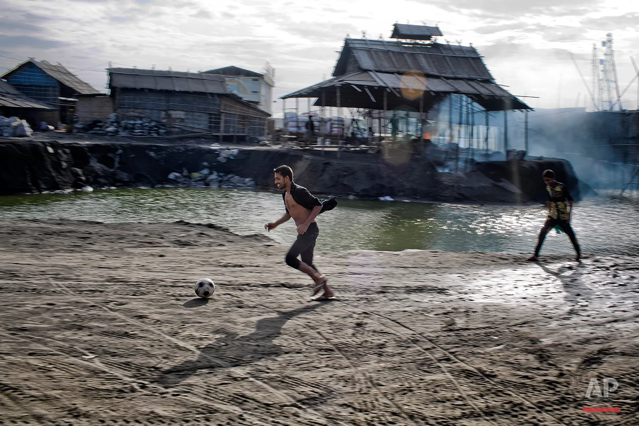 In this Aug. 6, 2016 photo, aluminum recycling worker Rubel Hossain plays soccer near a recycling factory on the outskirts of Dhaka, Bangladesh. A large swath of land not far from the Buriganga River is dotted with makeshift tents that are home to men and women who travel far from home to work 12 hours a day recycling cans, industrial ash and medicine blister packets into raw aluminum. The work is difficult and dangerous. The workers have no safety equipment or masks to protect themselves from the fumes and aluminum dust. (AP Photo/ A.M. Ahad)