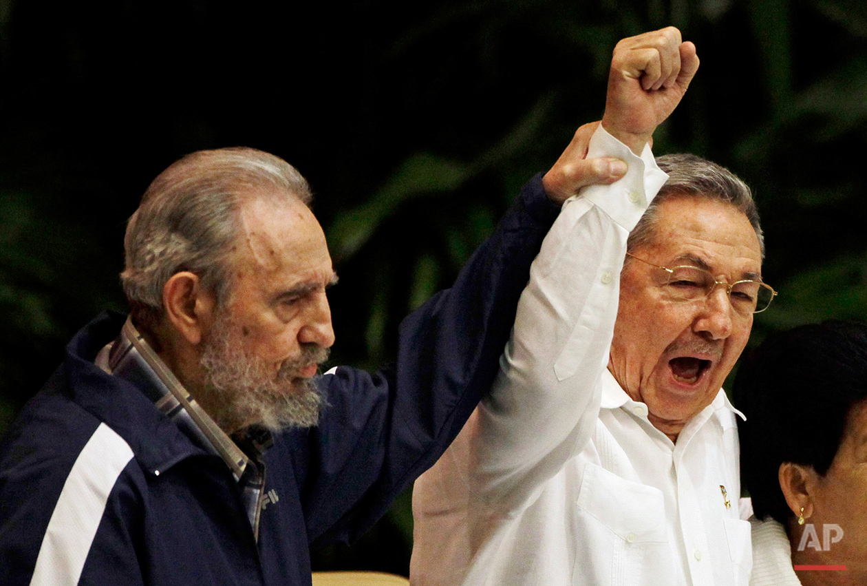  In this April 19, 2011 photo, Fidel Castro, left, raises his brother's hand, Cuba's President Raul Castro, center, as they sing the anthem of international socialism during the 6th Communist Party Congress in Havana, Cuba. As Fidel gets ready to cel