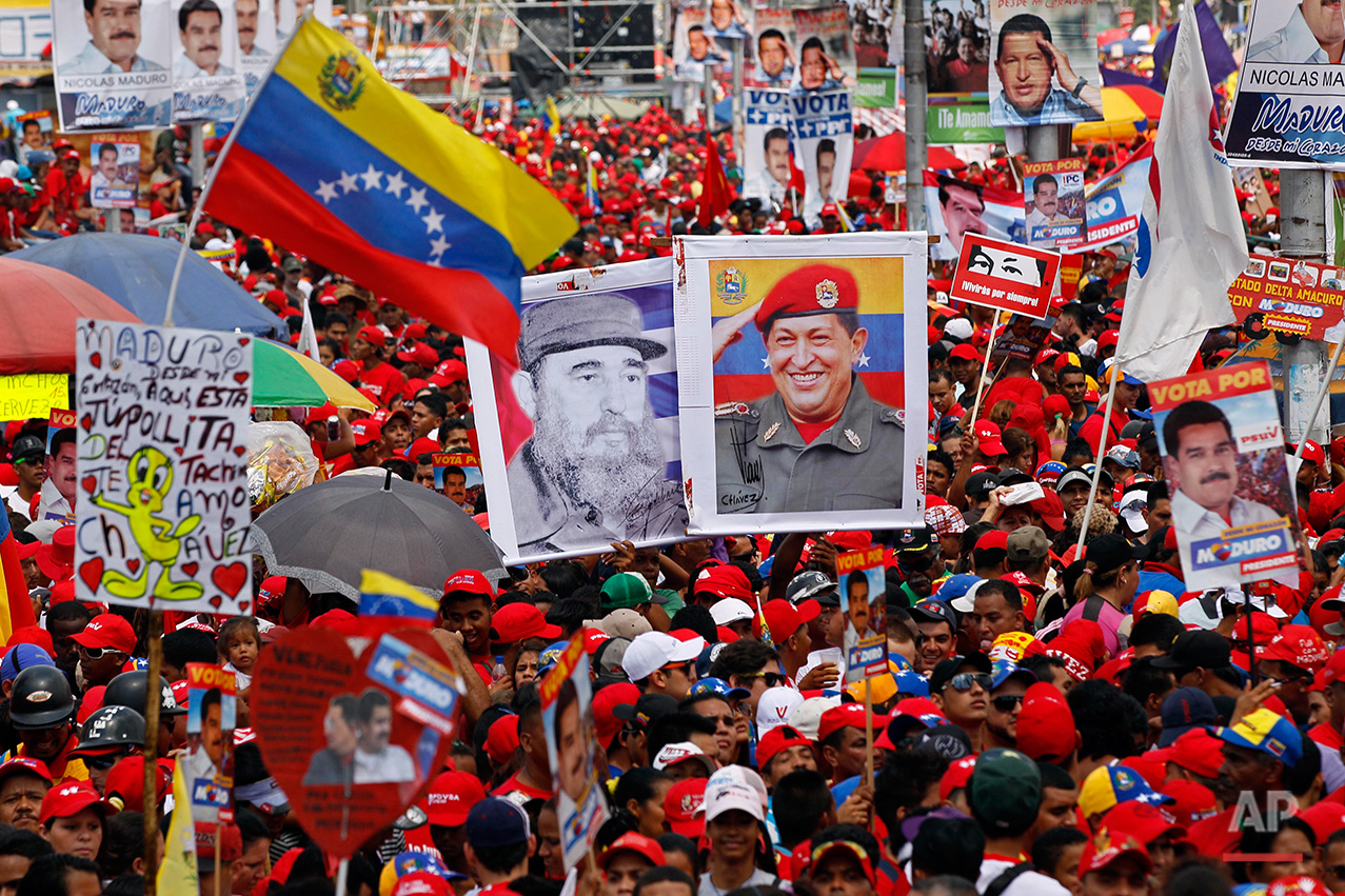  Holing images of Venezuela's late President Hugo Chavez, right, and Cuba's Fidel Castro, left, supporters attend the closing campaign rally for Venezuela's acting President Nicolas Maduro in Caracas, Venezuela, Thursday, April 11, 2013. (AP Photo/Ar