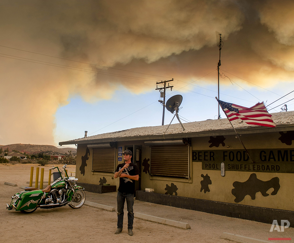 Moments before evacuation, Trevor Rainwater watches a wildfire burn into Summit Valley from the Joshua Inn in Hesperia Calif., on Sunday, Aug. 7, 2016. The fire, which broke out Sunday afternoon in the San Bernardino National Forest, prompted the evacuation order of the sparsely populated Summit Valley area east of the dam. (James Quigg/The Daily Press via AP)