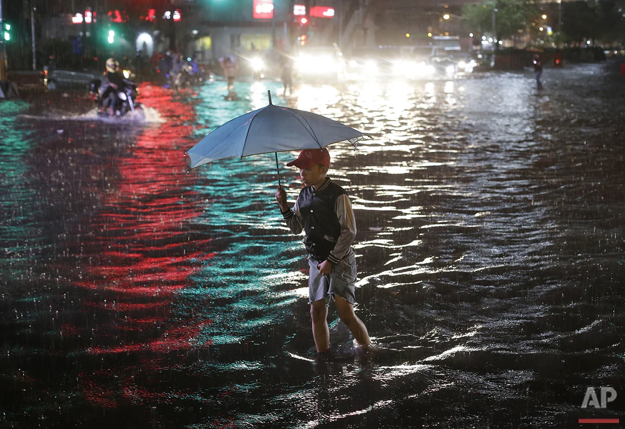 A boy crosses a flooded street during a heavy rain in Manila, Philippines on Friday, Aug. 12, 2016. Flooding snarled traffic around metropolitan Manila and stranded thousands of commuters. (AP Photo/Aaron Favila)