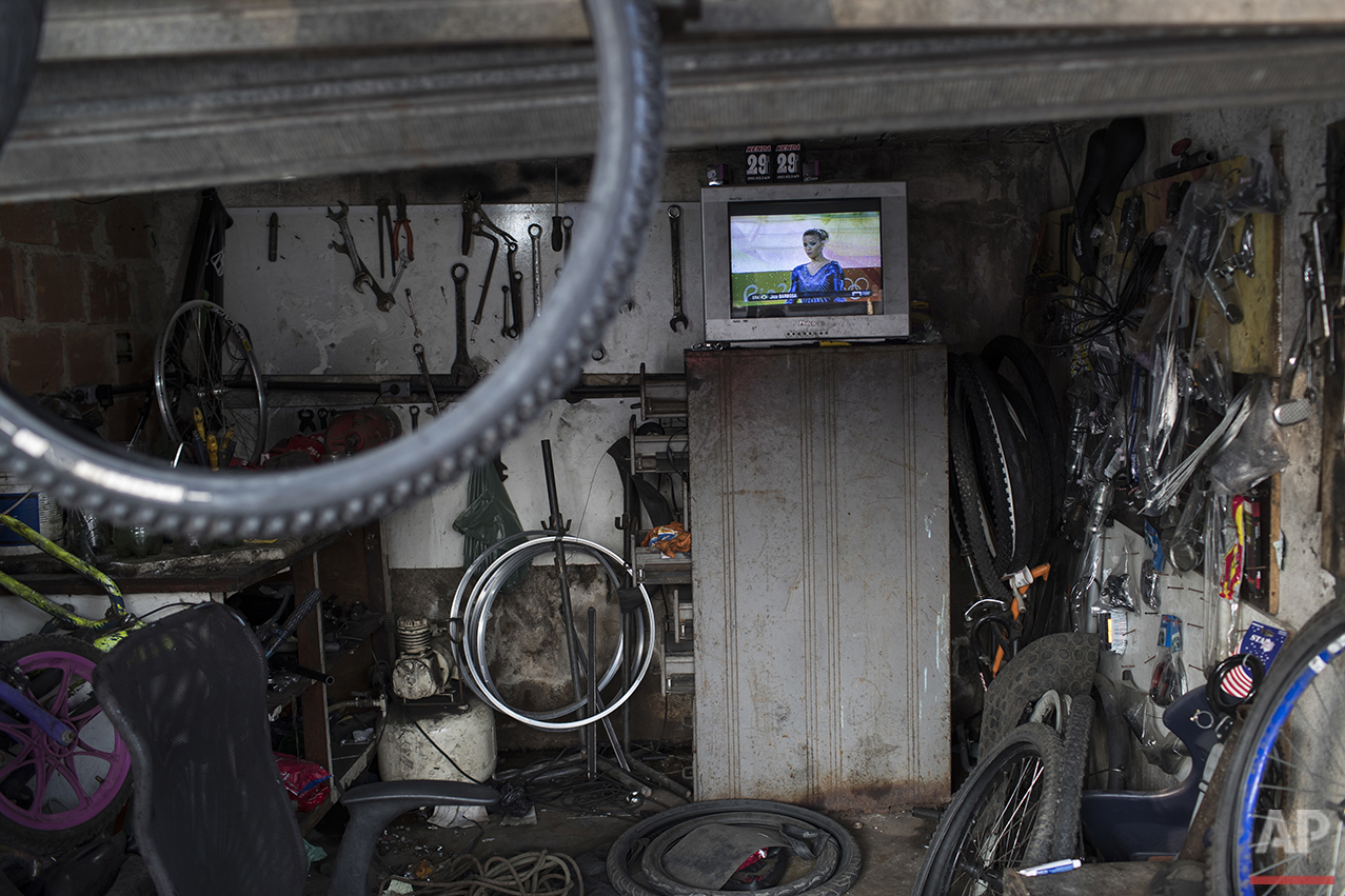 A television inside a bicycle repair shop shows the live transmission of Brazil's Jade Barbosa during the artistic gymnastics at the 2016 Summer Olympics in Rio de Janeiro, Brazil, Tuesday, Aug. 9, 2016. (AP Photo/Felipe Dana)