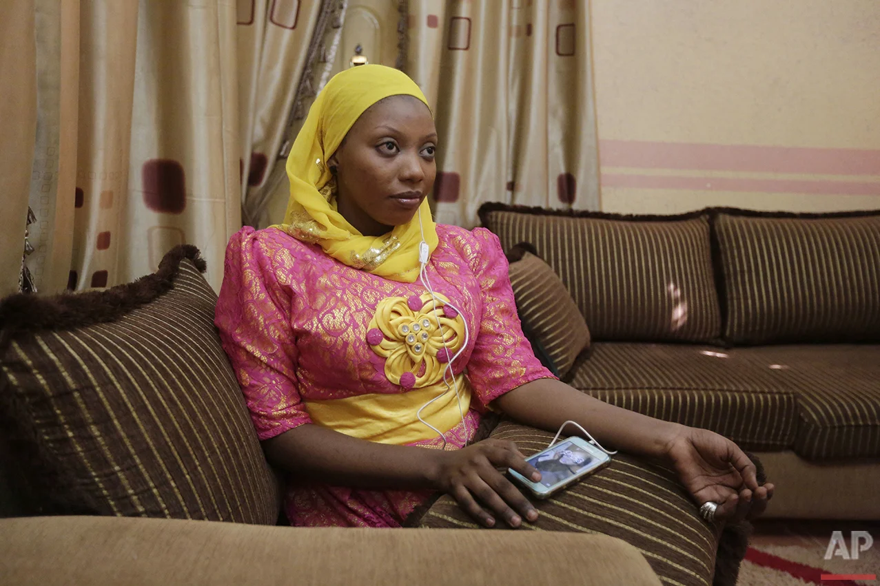  In this photo taken Tuesday, April 5, 2016, Khadija Gudaji, a Physics student at Northwest University, listens to a daily radio talk show on her mobile phone in Kano, Nigeria. In the local market, stalls are signs of a feminist revolution with piles