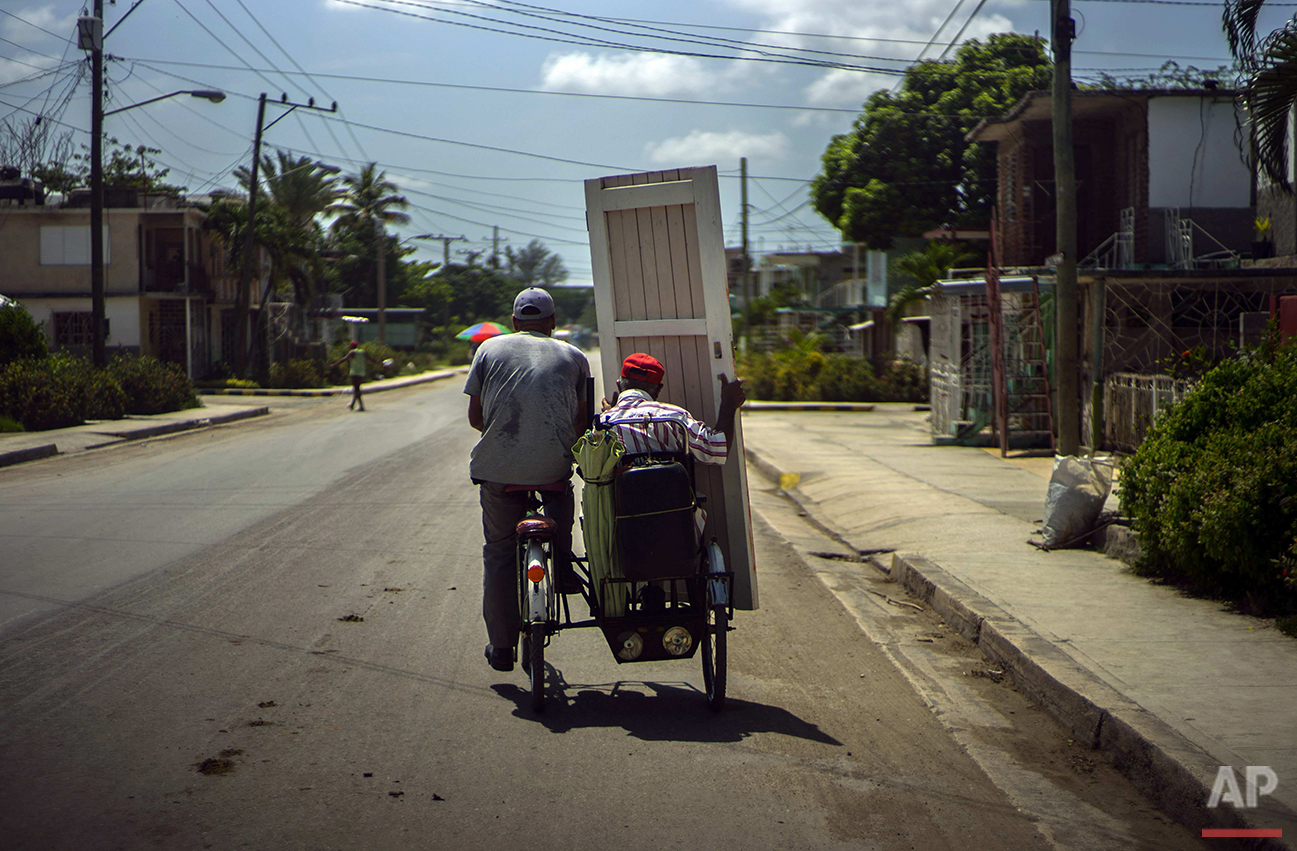  In this June 11, 2016 photo, a man carries a house door on the passenger side of a bicycle taxi in Holguin, Cuba, the region where Fidel Castro and his brother President Raul Castro were born and grew up. Fidel Castro has written of happy memories o
