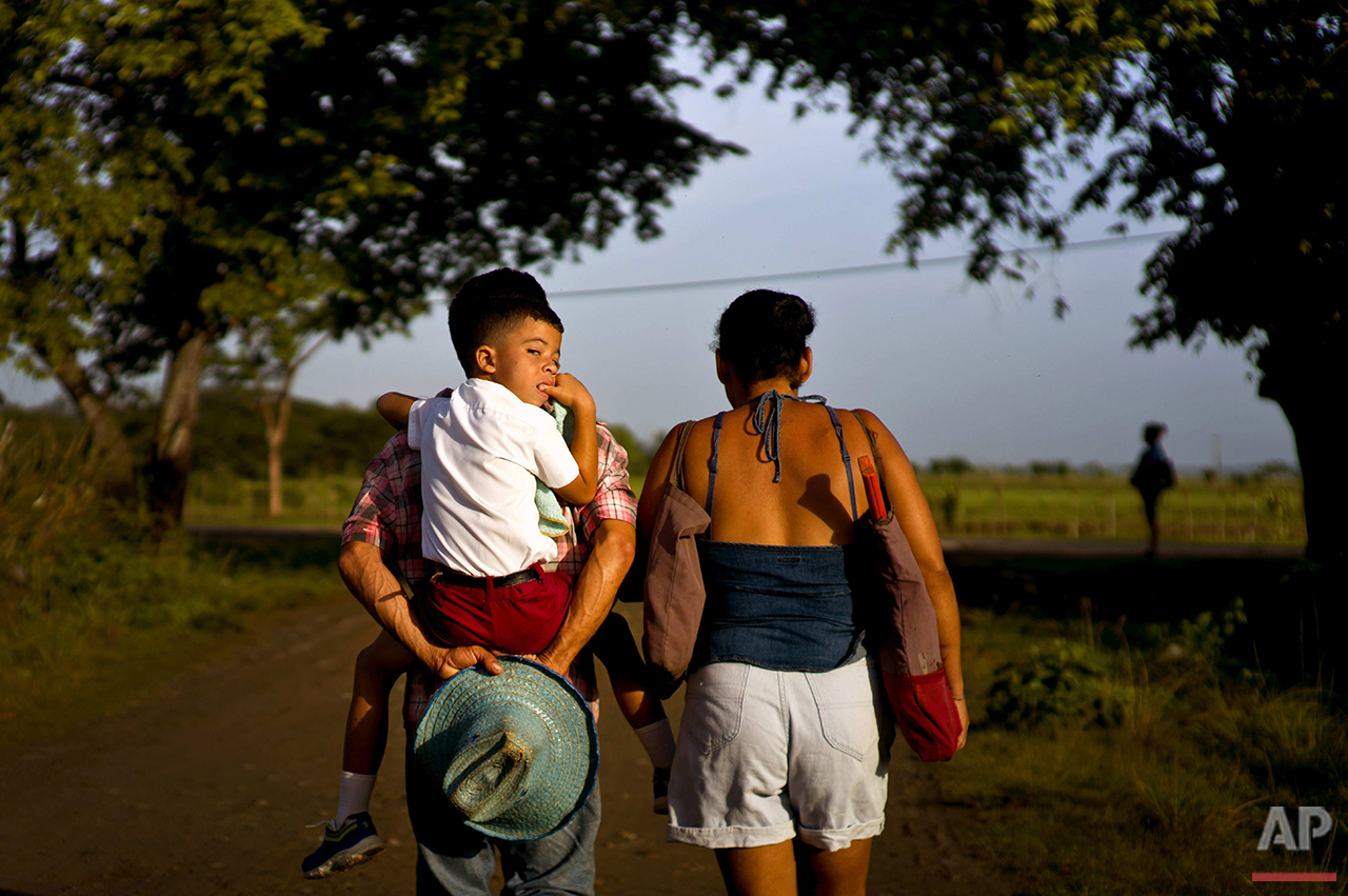  In this June 15, 2016 photo, four-year-old Kelvin Lopez Quintana gets an early morning piggyback ride to school from his father, along the road where the childhood home-turned-museum of Fidel Castro and his brother, President Raul Castro, is located