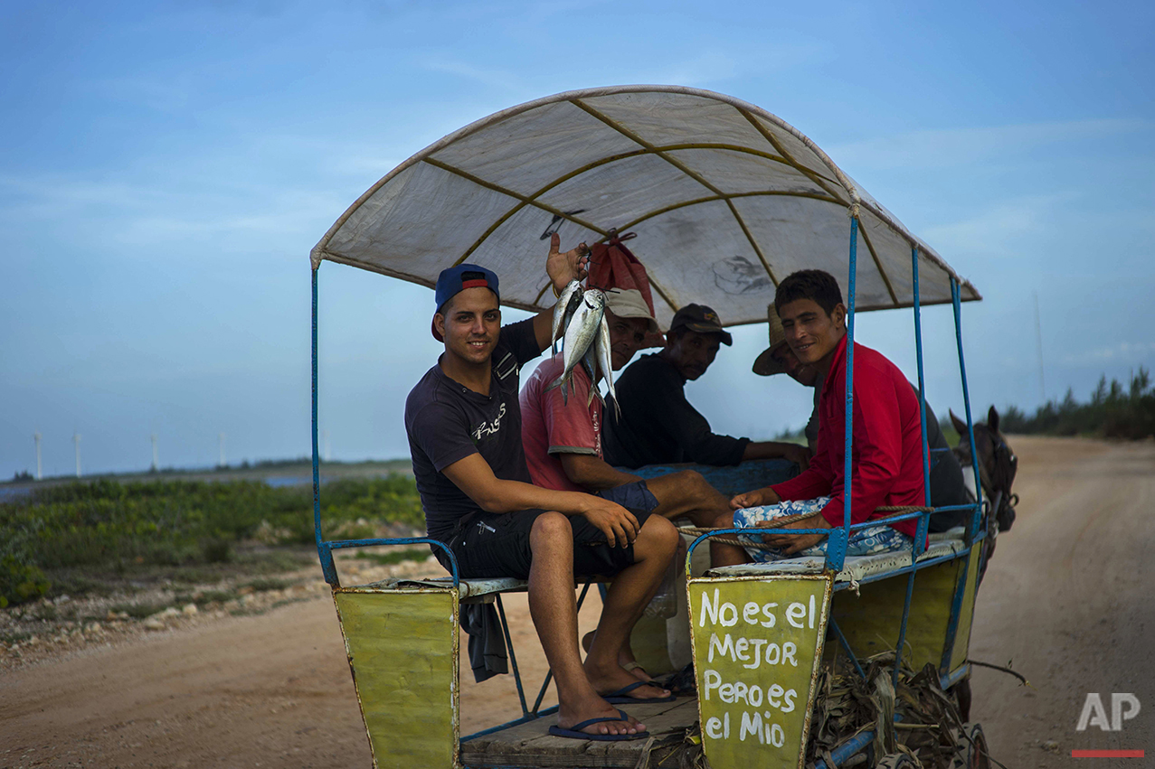  In this June 11, 2016 photo, a message that reads in Spanish "It's not the best but it's mine" adorns a horse-drawn wagon with men selling sea-caught fish as they ride along the coastline near Gibara in Cuba's Holguin province. Amid the rise in visi