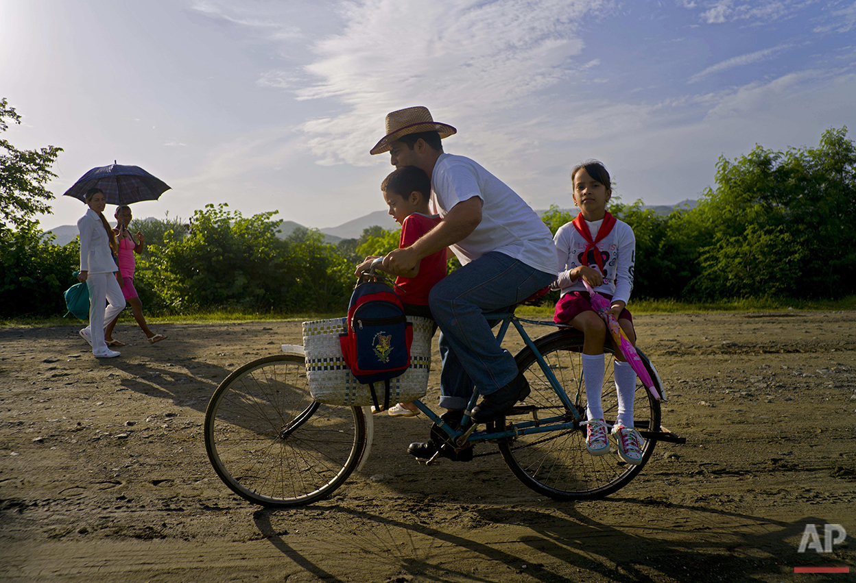  In this June 15, 2016 photo, Yosbani Rodriguez bikes his son Meiler and daughter Mayla to school before work in Biran, Cuba. Rodriguez, 33, works as the historian at the nearby home-turned-museum where Fidel Castro and his brother, current President