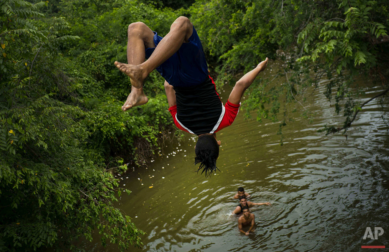  In this June 12, 2016 photo, a youth does a back flip from an overpass into the Mayari River as he and friends spend their Sunday afternoon in the village of Mayari, in Cuba's Holguin province where Fidel Castro grew up. Alcides Leyva, who directs t