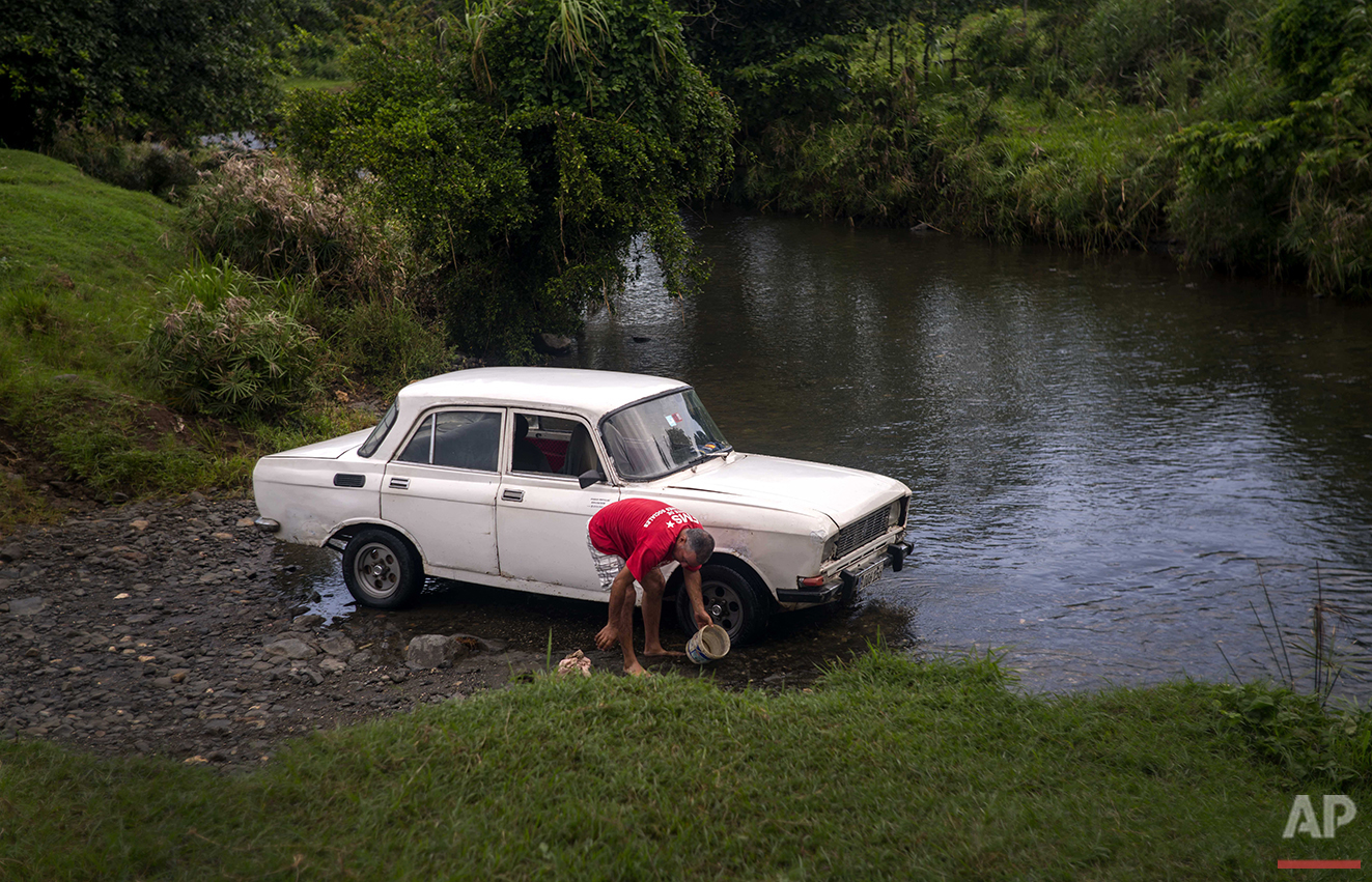  In this June 10, 2016 photo, government contracted driver Ricardo Reidy washes a Soviet-made car in the Biran River near the home-turned-museum where Fidel Castro and his brother, President Raul Castro, were born in Biran, Cuba. (AP Photo/Ramon Espi
