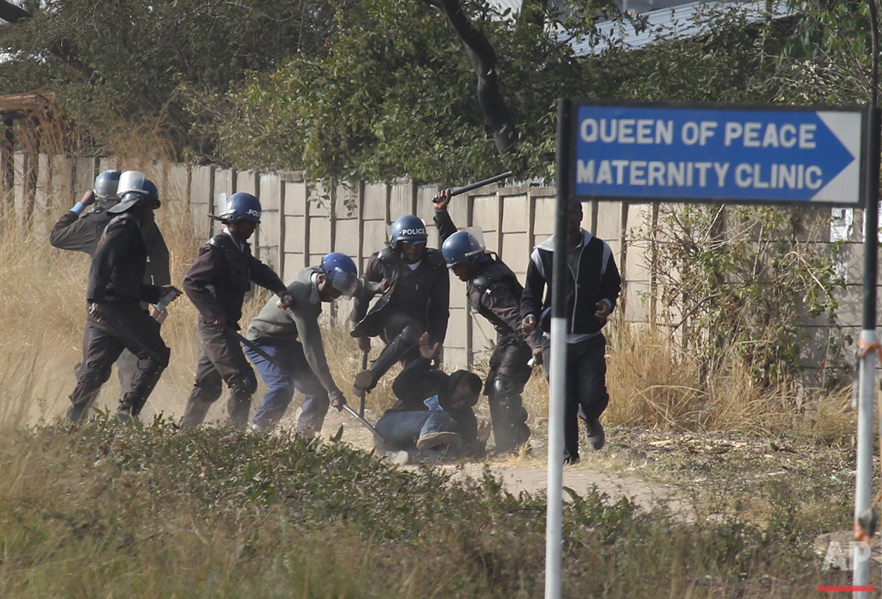  Armed police surround a rioter in Harare, Zimbabwe on Monday, July, 4, 2016. Police in the capital fired tear gas and water cannons in an attempt to quell rioting by taxi and mini bus drivers protesting what they describe as police harassment. The v