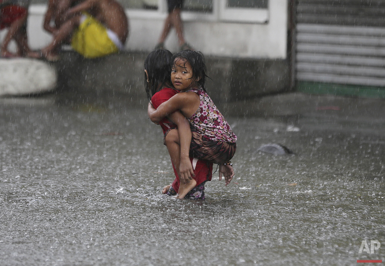 A girl is carried along a flooded road in suburban Mandaluyong, east of Manila, Philippines, as monsoon downpours intensify while Typhoon Nepartak leaves the country on Friday, July 8, 2016. (AP Photo/Aaron Favila) 
