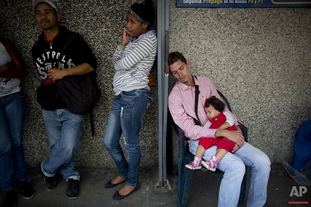  In this Tuesday, May 3, 2016 photo, people wait in line to buy food outside a supermarket in Caracas, Venezuela. Prices have been driven impossibly high by scarcity, hoarding and black market resellers, forcing Venezuelans to line up again and again