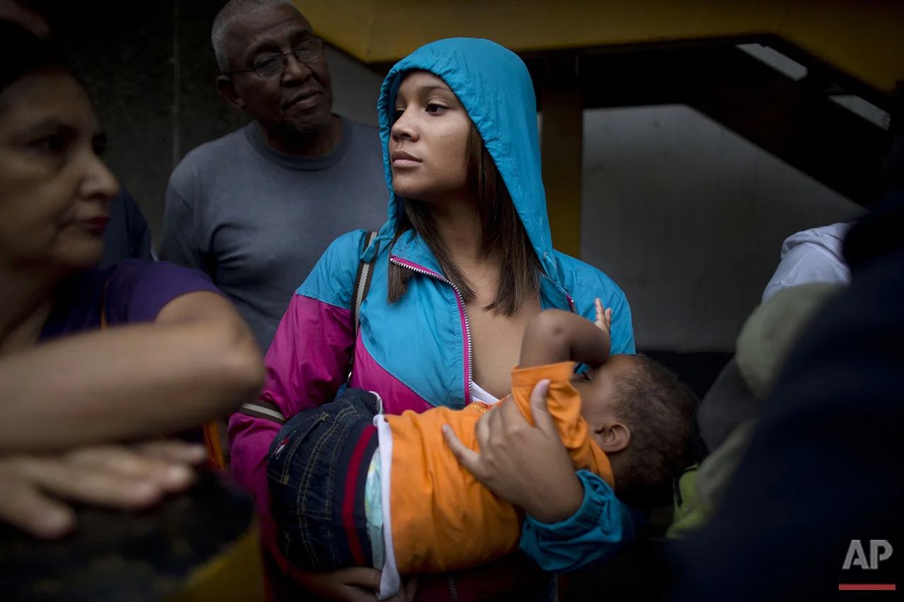  In this Tuesday, May 3, 2016 photo, Madeley Vasquez, 16, breast feeds her one-year-old son Joangel as she waits line outside a supermarket to buy in Caracas, Venezuela, Tuesday, May 3, 2016. Vasquez once had to run down the block to avoid getting ca