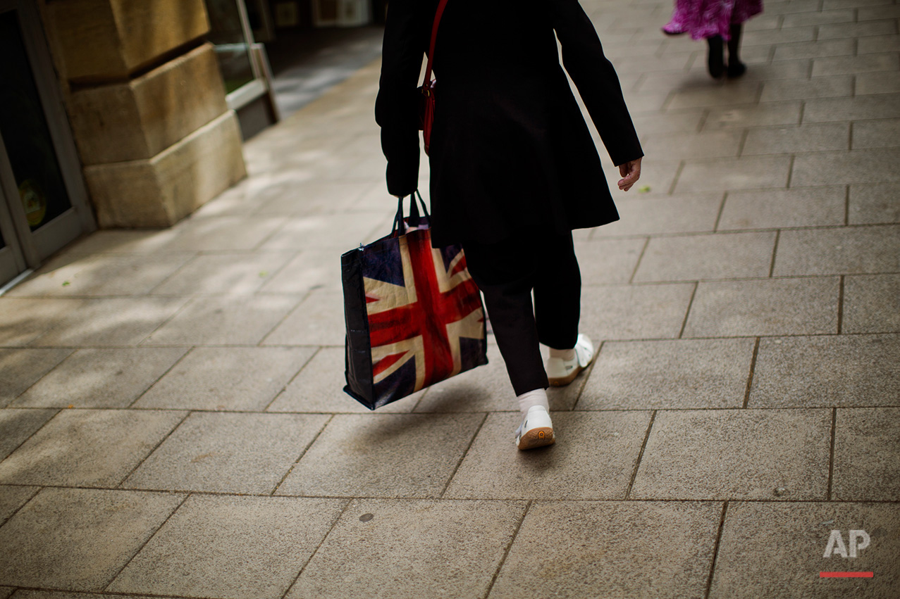  In this Tuesday, July 5, 2016 photo, a woman carrying a bag decorated with a Great Britain's union flag, walks a long a street in downtown Peterborough, East of England. Many people who voted for Britain to get out of the European Union look at mult