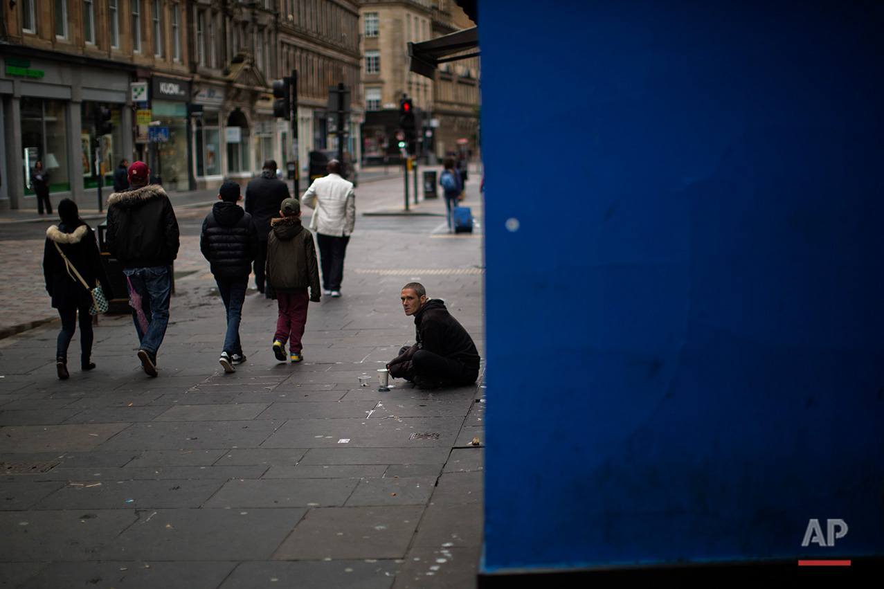  In this Sunday, July 3, 2016 photo, people walk by a beggar at a street in downtown Glasgow, Scotland. In one of the defining splits of last week’s EU referendum, all 32 council areas in Scotland as well as Northern Ireland voted for Britain to stay