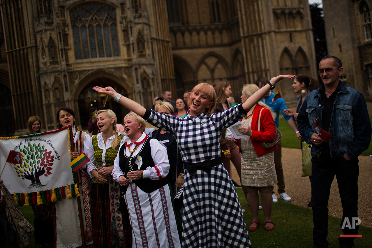  In this Wednesday, July 6, 2016 photo,  Lithuanians sign their national anthem during a ceremony in front of the Saint Peter's Cathedral in downtown Peterborough, East of England. On Wednesday about 100 Lithuanians, some wearing traditional costumes