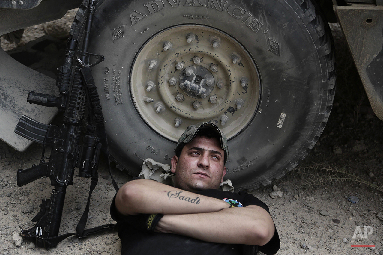  In this Wednesday, June 8, 2016 photo, Sgt. Ahmed Kamel, 26, of Iraq's elite counterterrorism forces, rests during the midday heat at a battle position on the southern edge of Fallujah, Iraq. He has three tattoos: the name of his brother, Saadi, who