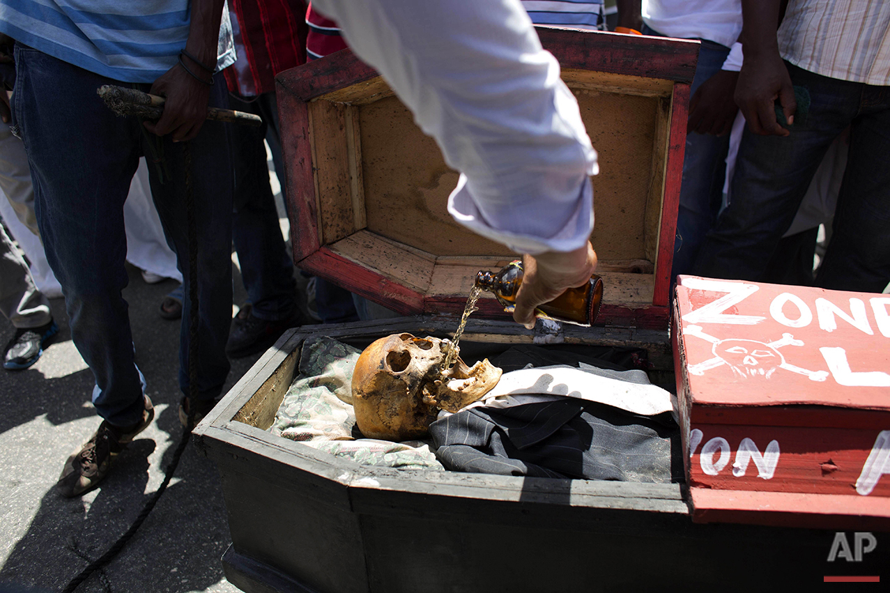  A supporter of PHTK presidential candidate Jovenel Moise pours beer into a skeleton representing interim President Jocelerme Privert in a mock coffin, during a voodoo ceremony before the start of a protest march demanding his resignation in Port-au-