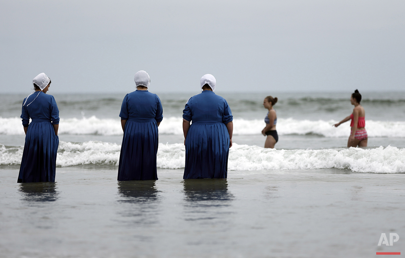  From left, Joanne Steury, Margerie Steury and Rosa Graber stand in Pacific Ocean waters for the first time during a family trip from their Amish community in Michigan, to Coronado, Calif., on Thursday, June 9, 2016. (AP Photo/Gregory Bull) 