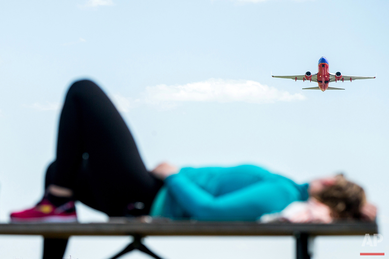 A plane takes off from Washington's Ronald Reagan National Airport as Julia Hurley, of Washington, relaxes on a picnic table at Gravelly Point Park in Arlington, Va., Wednesday, June 8, 2016, after bicycling to Mt. Vernon and back. (AP Photo/Andrew 