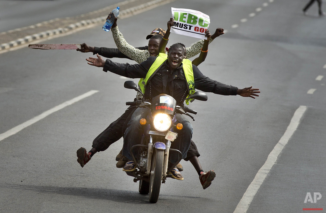  Protesters on a motorcycle hold a placard using the acronym of the national electoral commission as they drive ahead of others on foot calling for the disbandment of the commission over allegations of bias and corruption, in downtown Nairobi, Kenya 