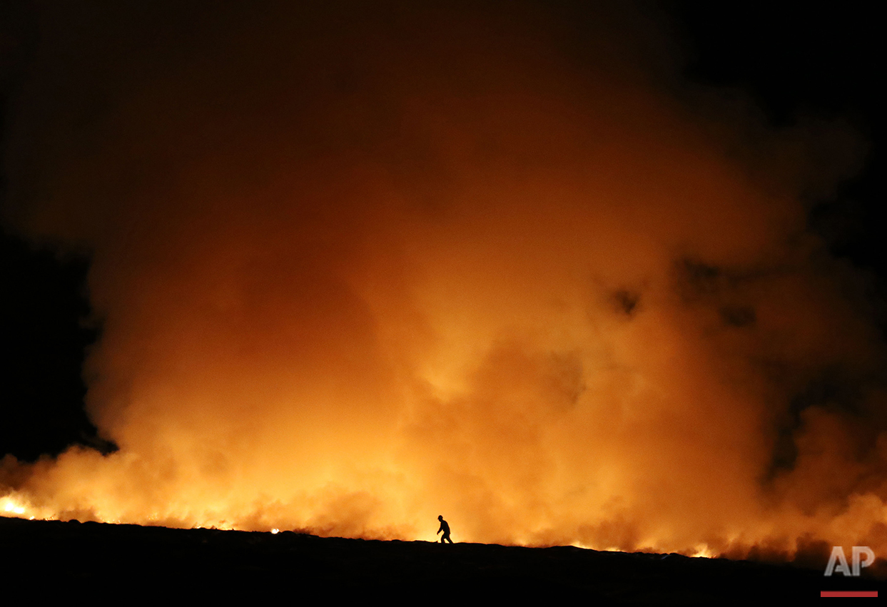  A firefighter walks past flames at the Douglas County landfill in Roseburg, Ore. on Saturday, June 4, 2016. (Michael Sullivan/The News-Review via AP) 