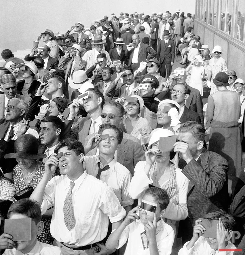 Eclipse watchers squint through protective film as they view a partial eclipse of the sun from the top deck of New York's Empire State Building Aug. 31, 1932. (AP Photo)