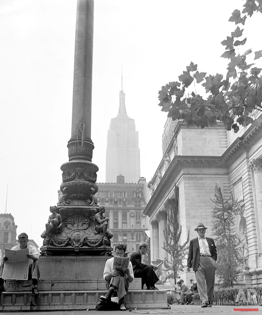  New York City, known the world over for its hustle-and-bustle, has its peaceful side also. Here a group of men take time out from their daily work to relax and read as they sit on the base of the flagpole on the New York Public Library grounds, Sept