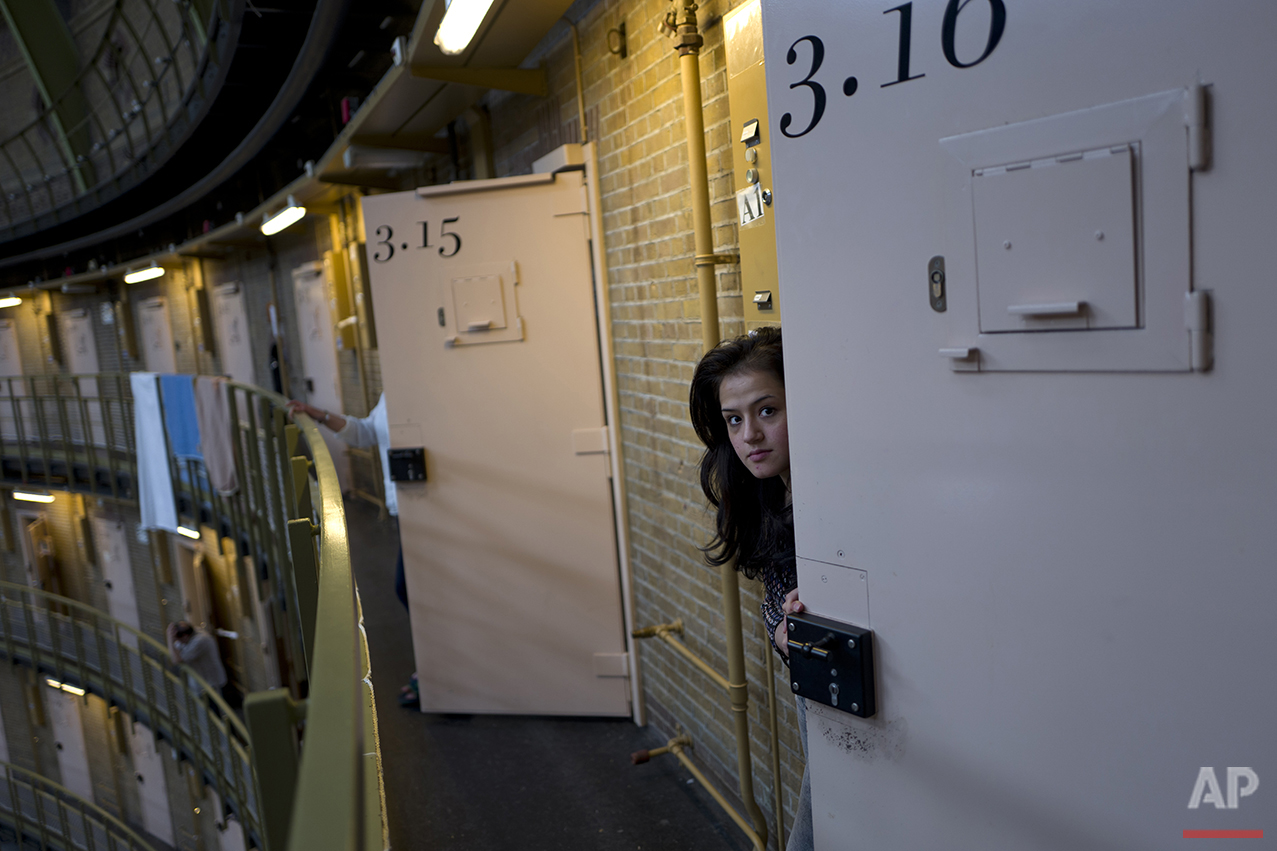  In this Saturday, May 7, 2016 photo, Afghan refugee Shazia Lutfi, 19, peeks through the door of her room at the former prison of De Koepel in Haarlem, Netherlands. The government has let Belgium and Norway put prisoners in its empty cells and now, a